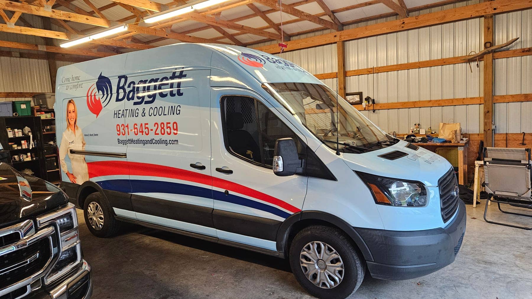 Ford Transit van wrapped with Baggett Heating and Cooling branding and phone number, inside the install bay
