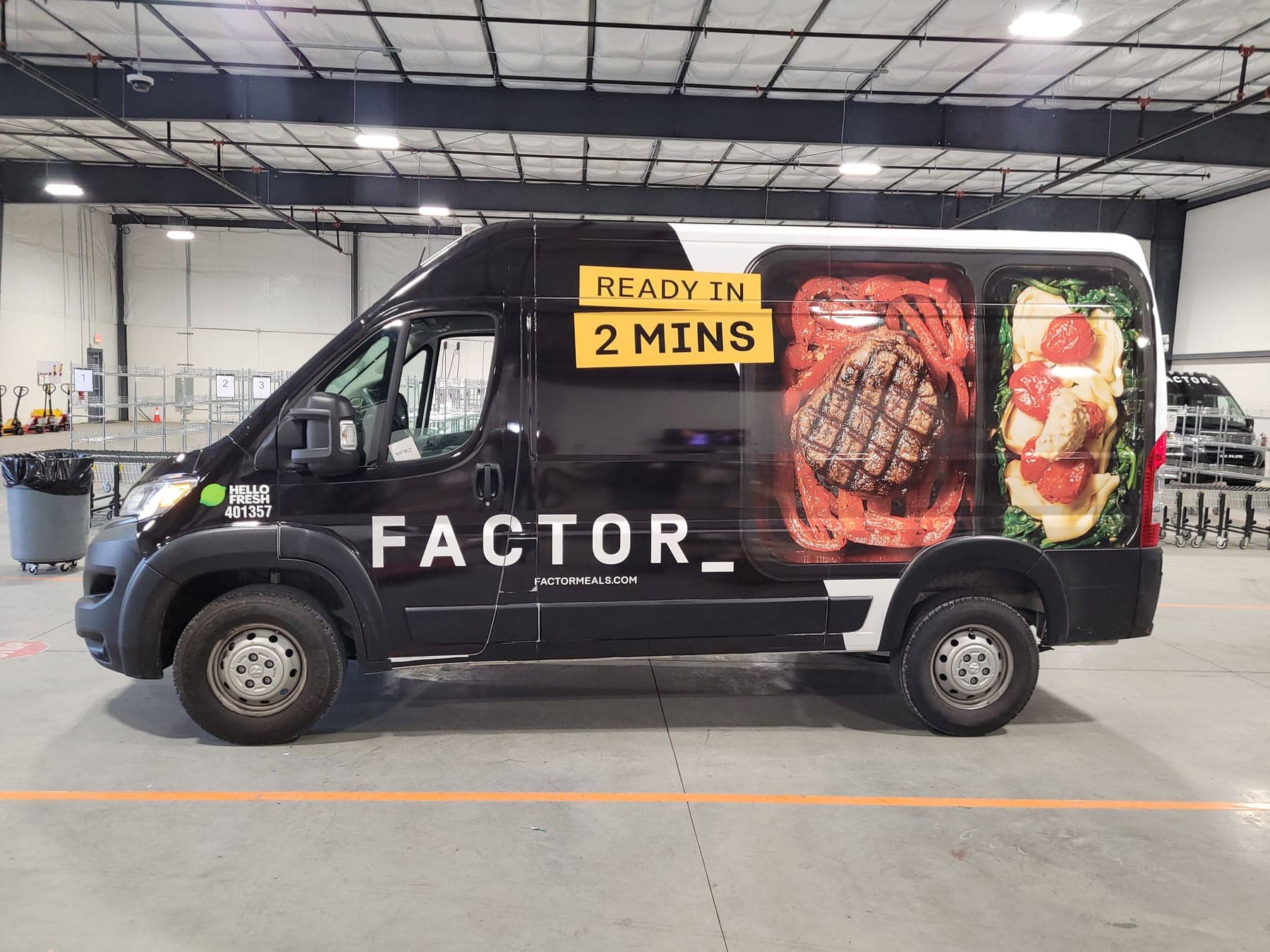 Three matching black Ram ProMaster vans with Factor meal graphics lined up in a warehouse