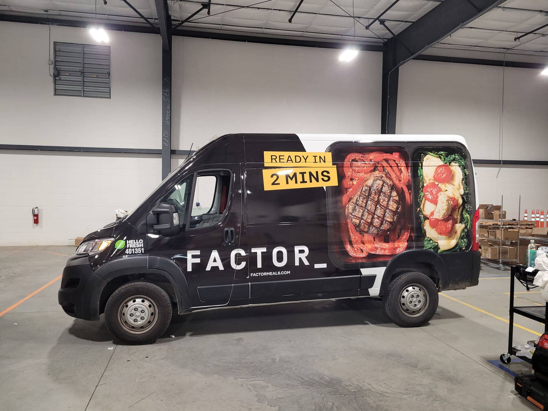 Side view of a black Factor delivery van showing plated-meal photography across the panel