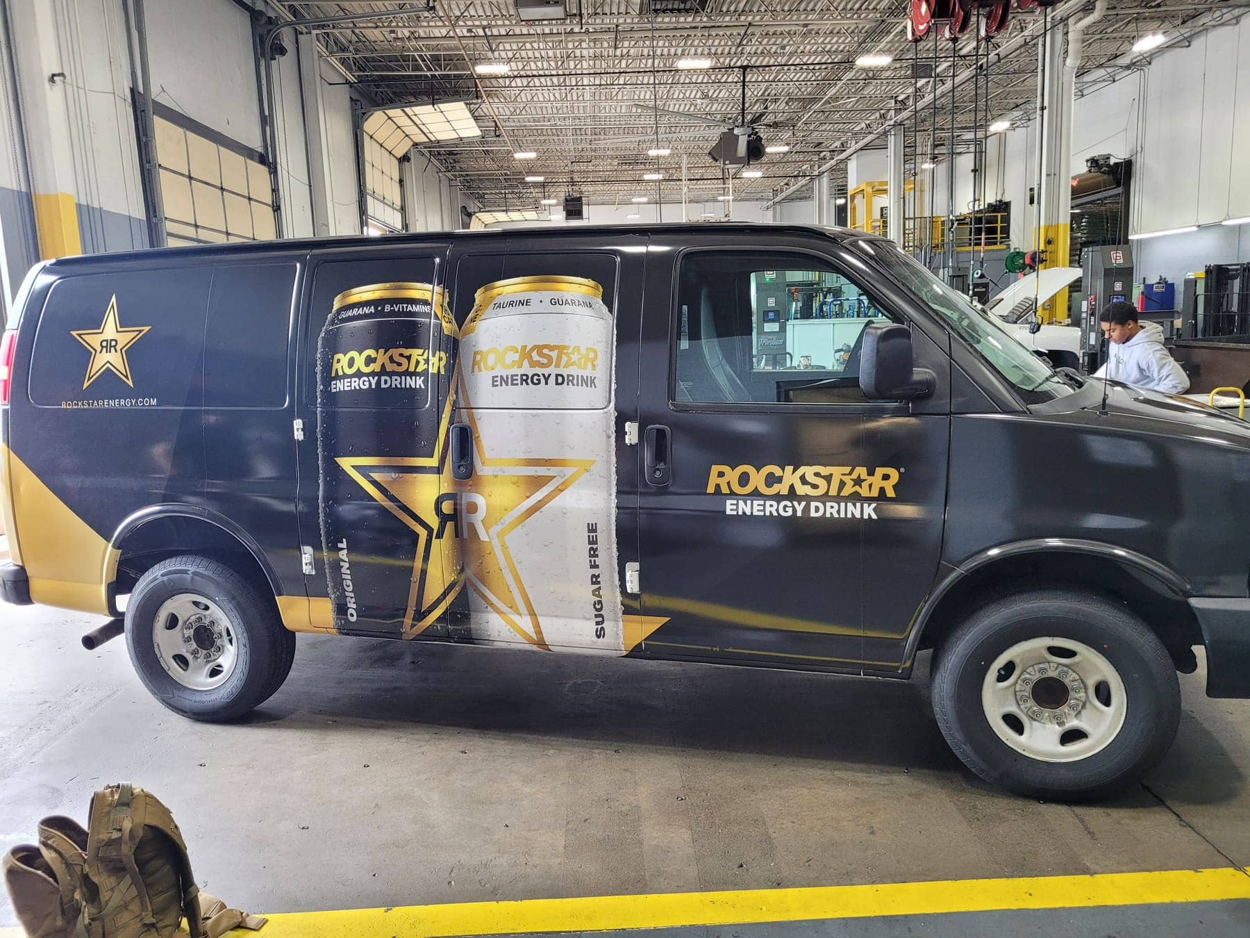Black Chevy Express van wrapped with gold Rockstar Energy logos and product graphics
