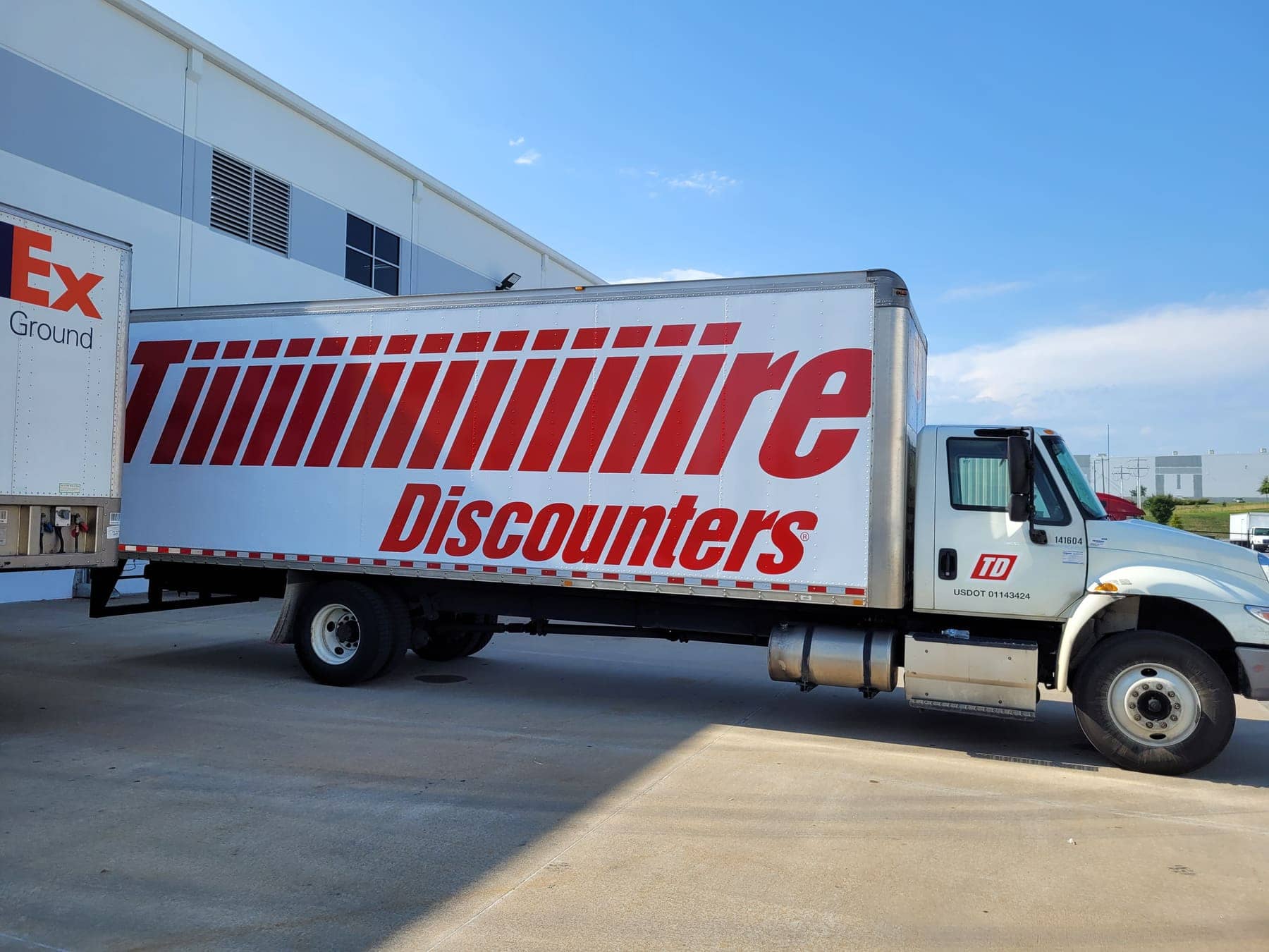 Tire Discounters box truck with red tire-tread lettering pulling out of a lot