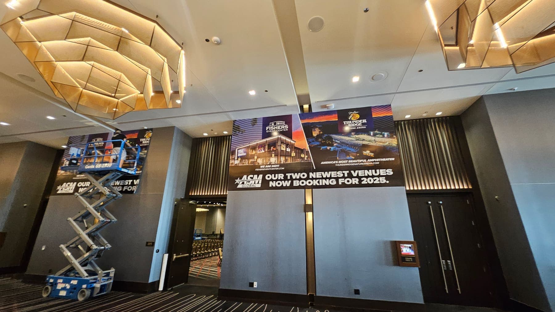 Banner wall graphics being installed at an ASM Global venue with a scissor lift