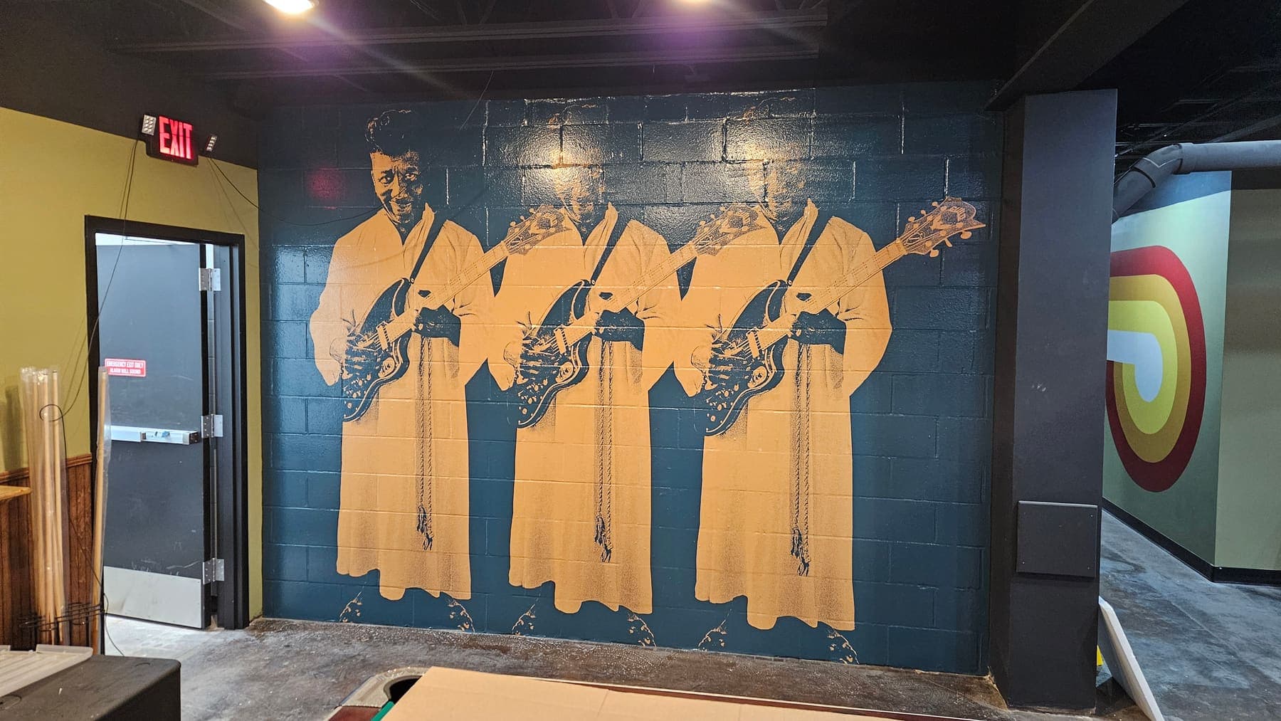 Repeated gold-on-navy blues guitarist artwork covering an interior brick wall