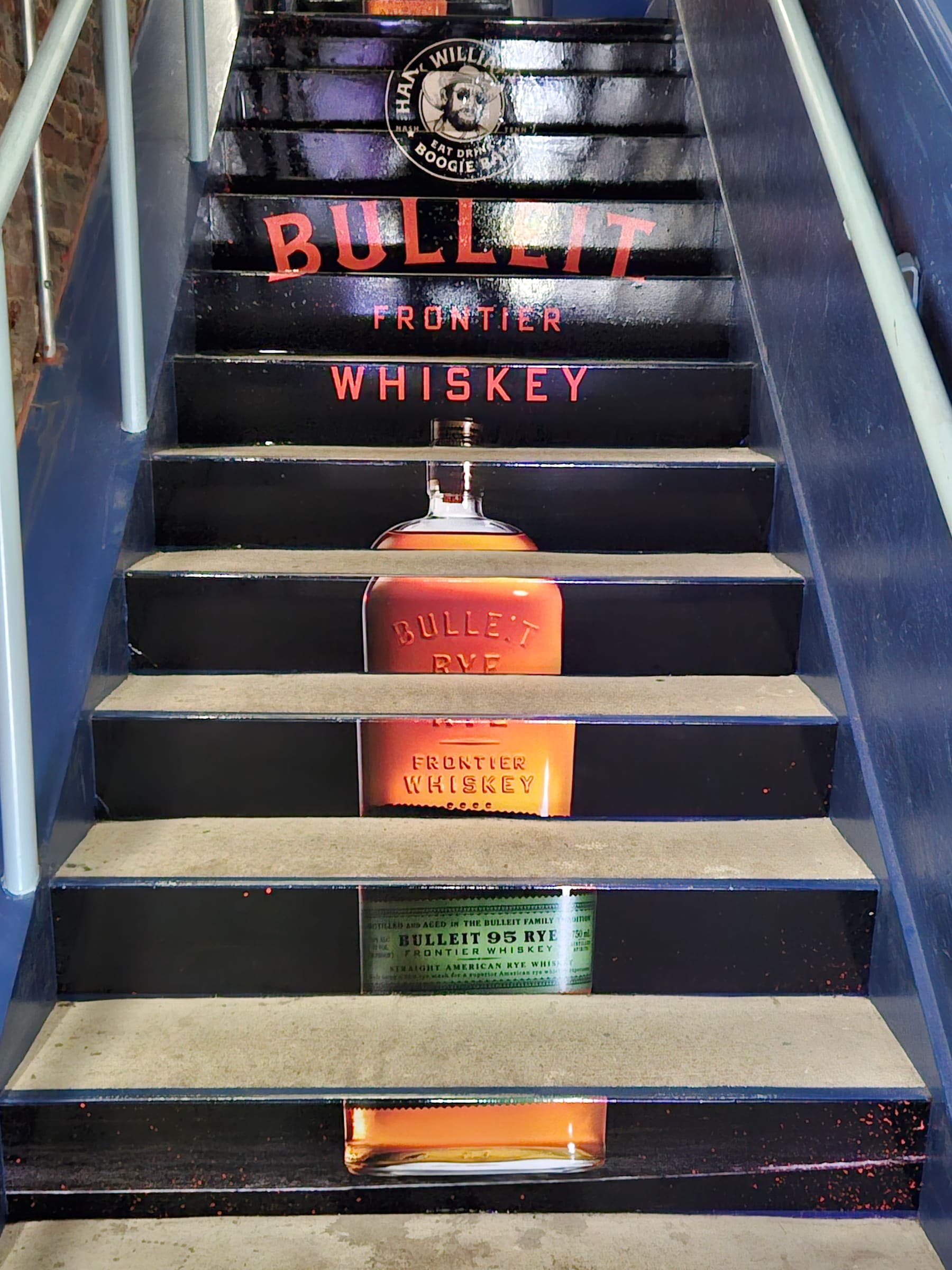 Stairway risers printed with Bulleit Frontier Whiskey bottle artwork at a venue