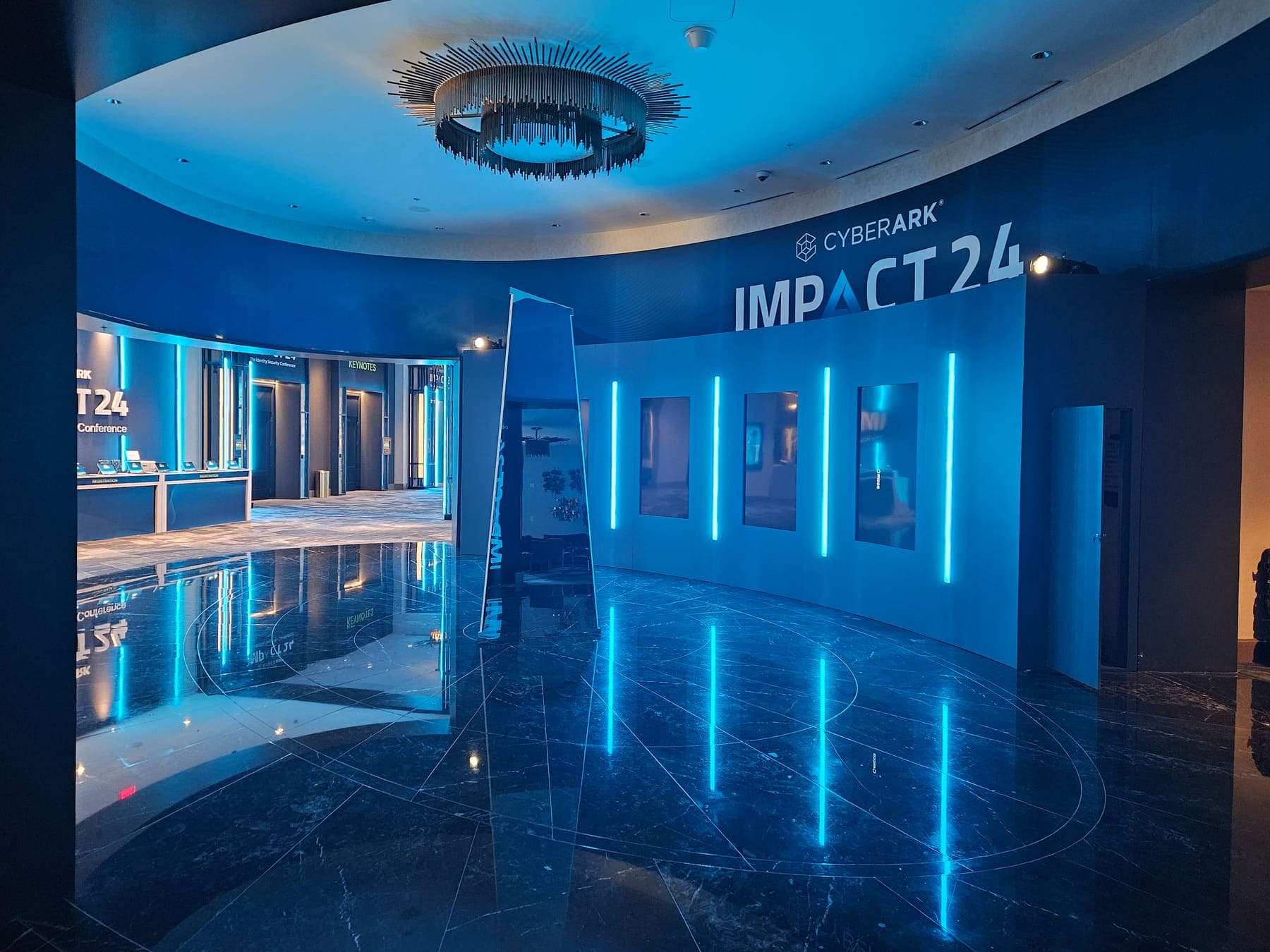 Dark conference entrance corridor with backlit blue CyberArk Impact 24 graphics