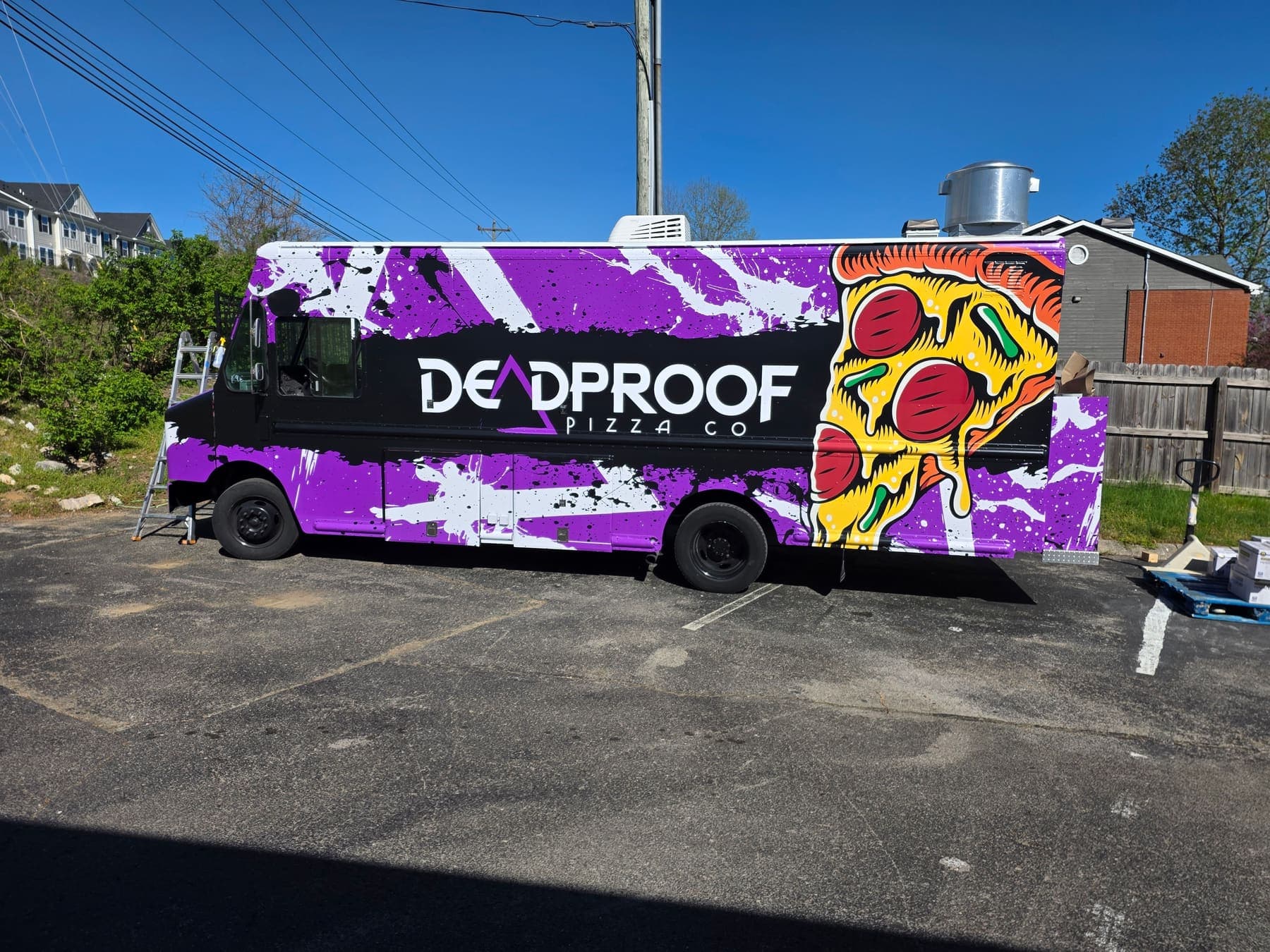 Purple and black Deadproof Pizza Co food truck wrapped with a painted slice of pizza
