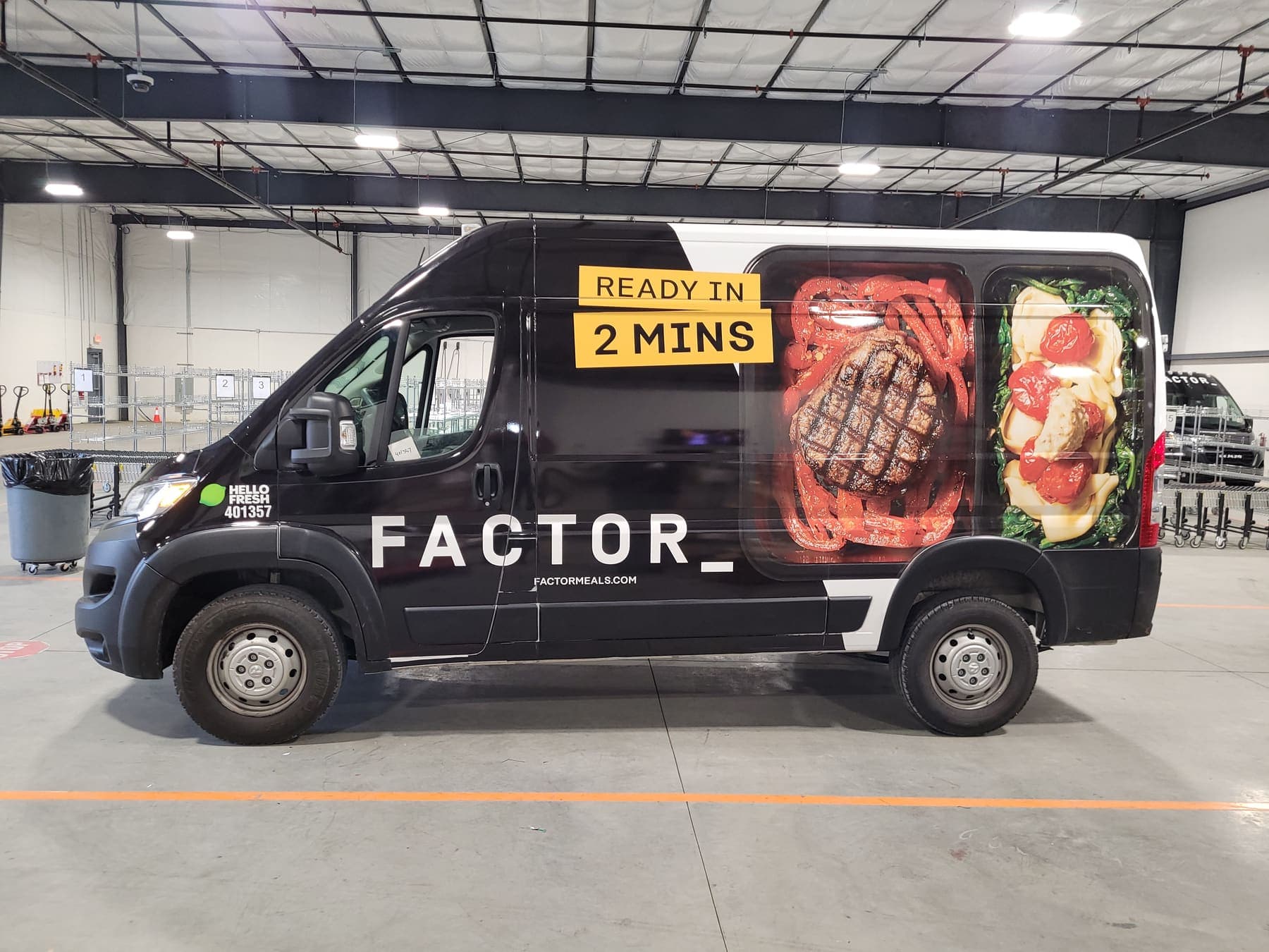 Three matching black Ram ProMaster vans with Factor meal graphics lined up in a warehouse