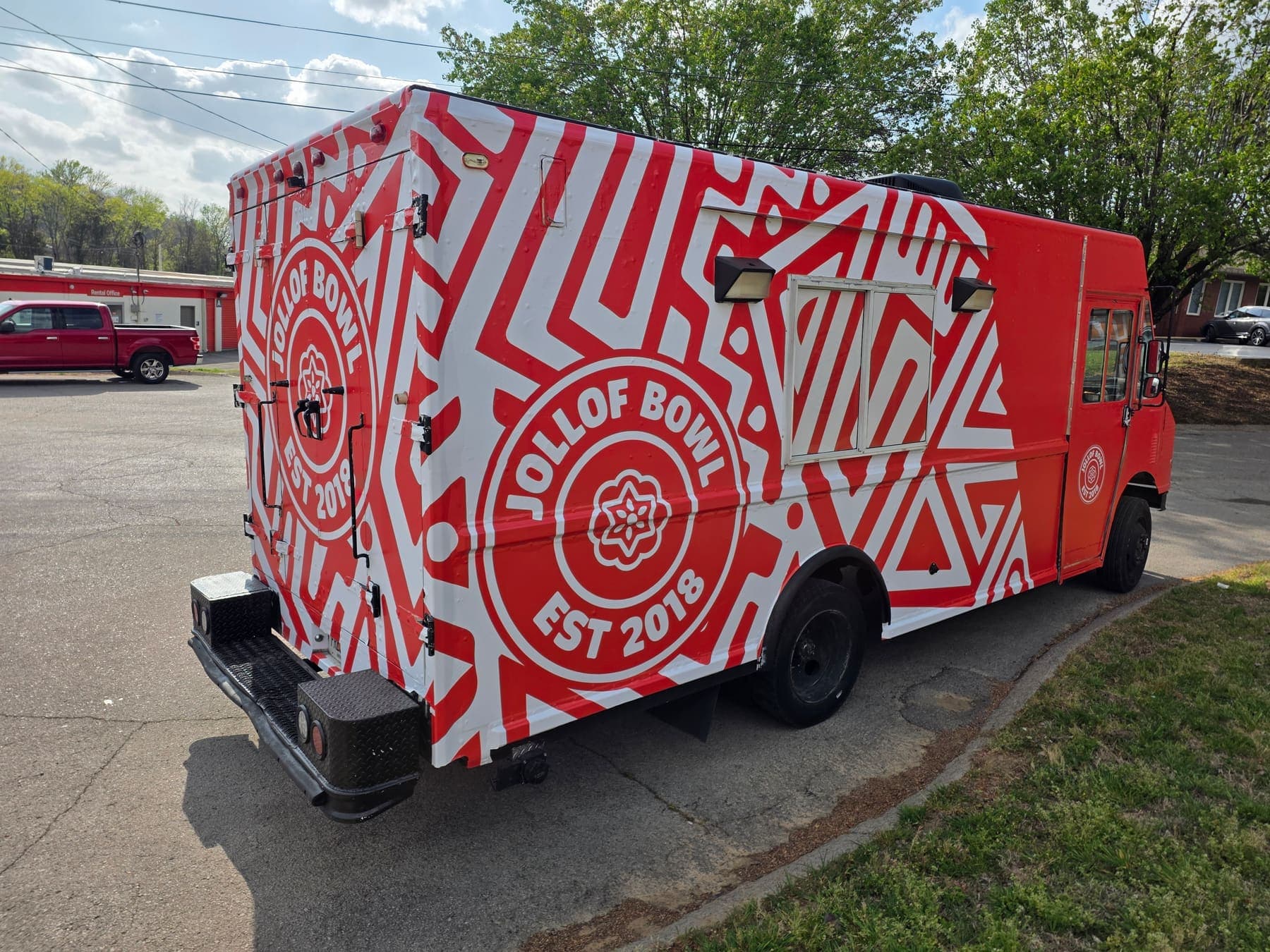 Red and white Jollof Bowl food truck wrapped in a bold geometric pattern with a circular logo
