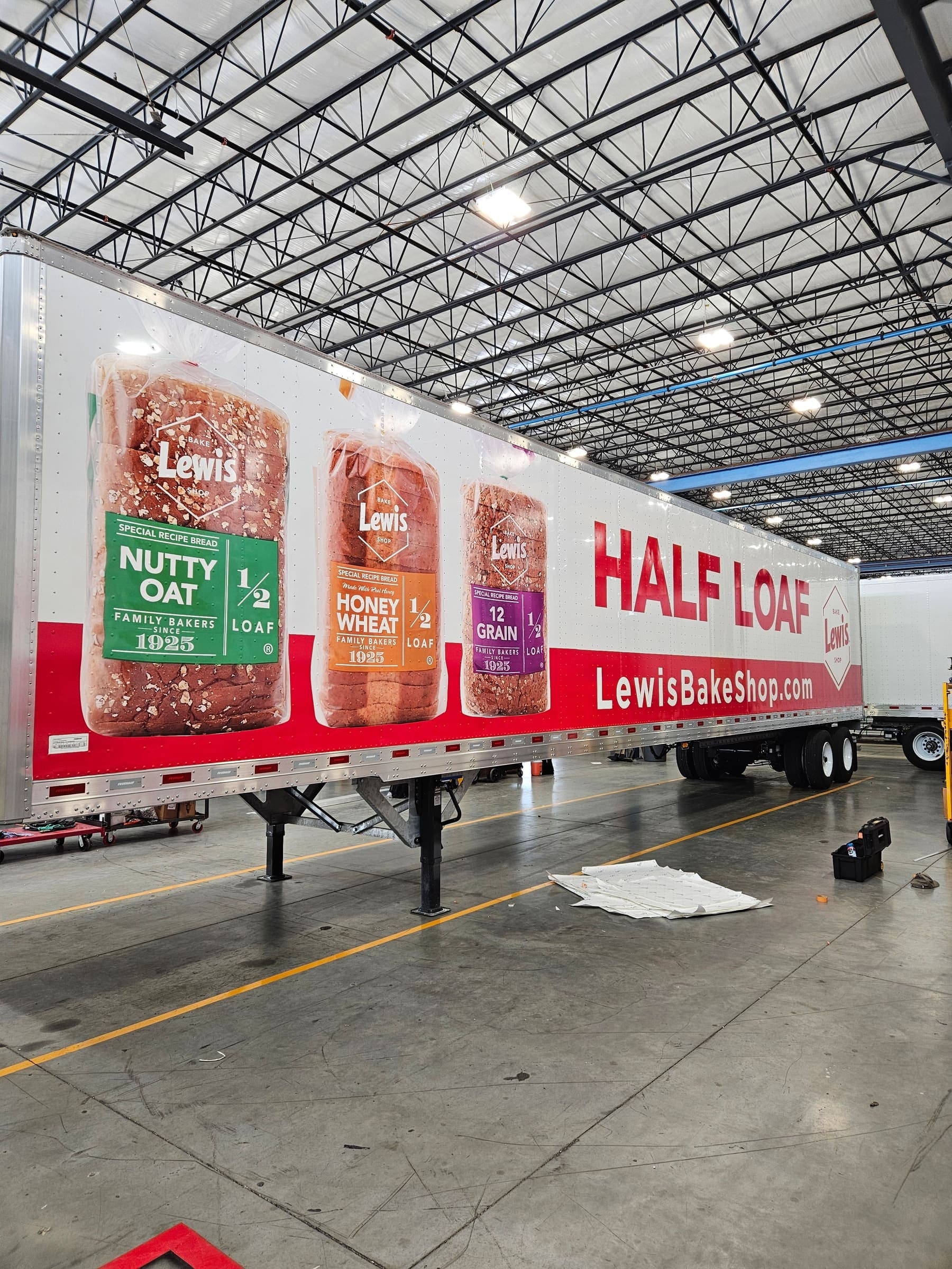 Trailer side detail showing Nutty Oat and Honey Wheat half-loaf packages at giant scale