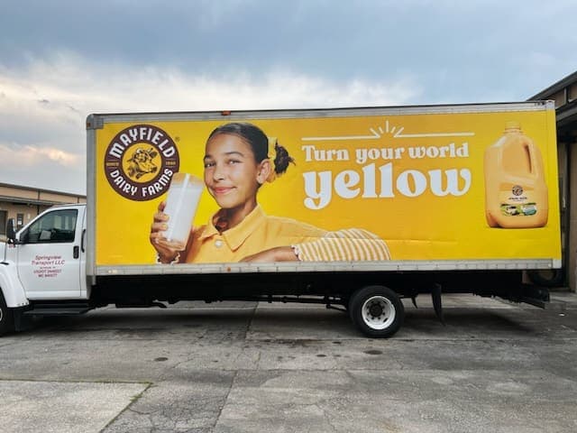 Bright yellow Mayfield Dairy Farms box truck wrap with milk-jug photography