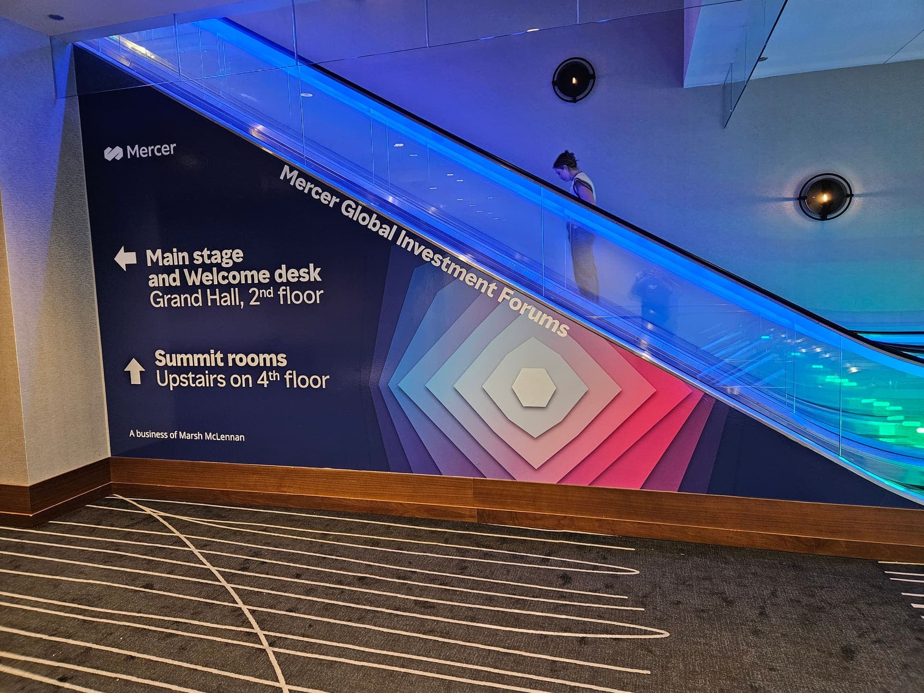 Escalator side panels wrapped in blue gradient Mercer wayfinding graphics