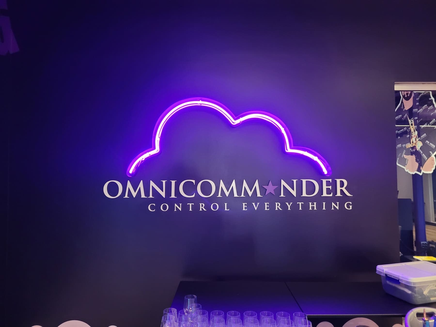 Purple neon cloud-and-lightning OMNICOMMANDER sign glowing on a dark lobby wall