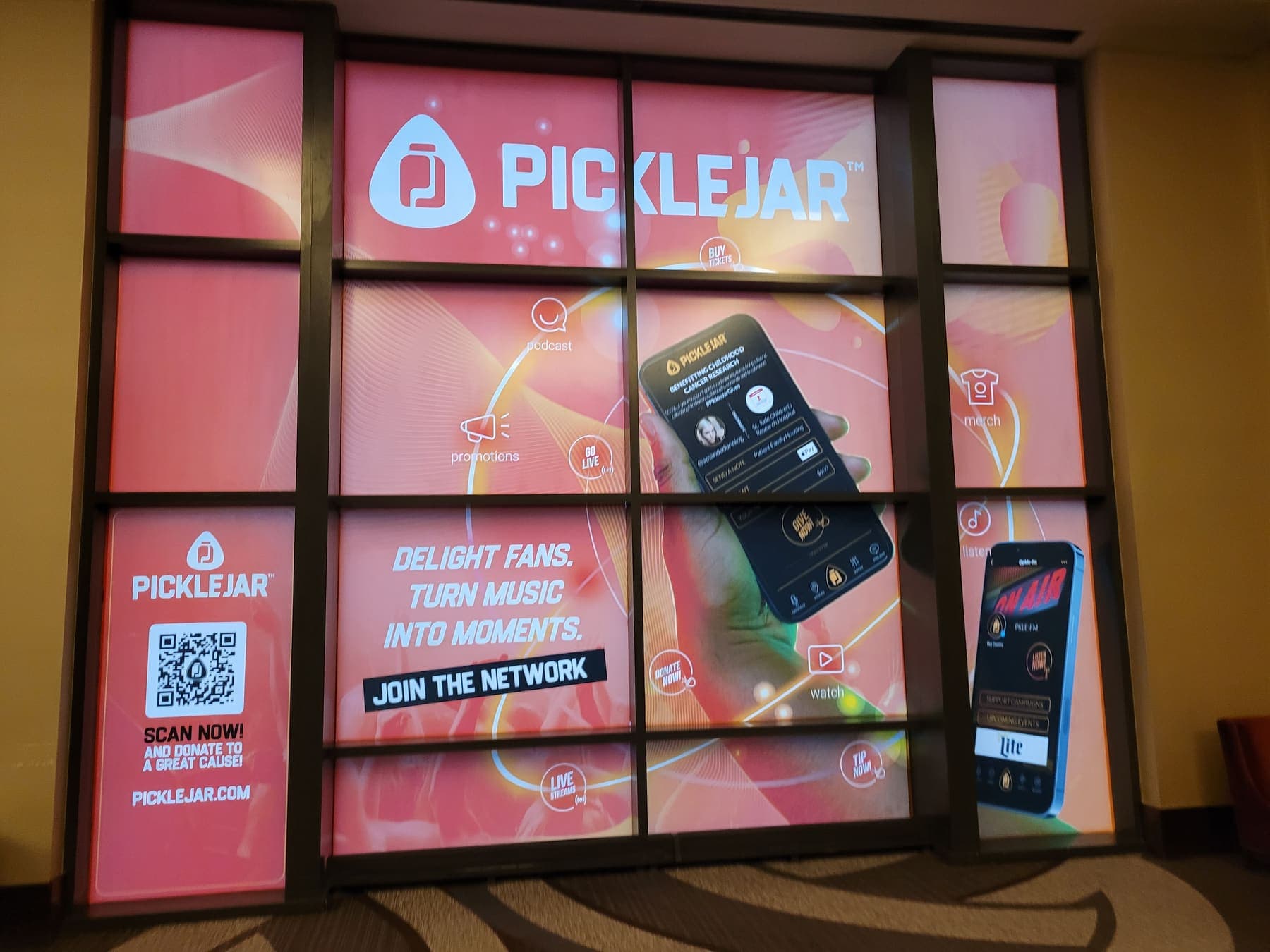 Backlit pink window display promoting the PickleJar live-music app with phone mockups