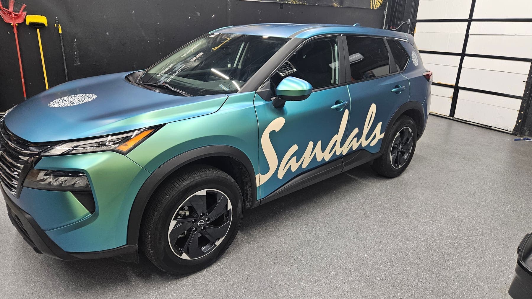 Nissan Rogue in a teal-to-purple satin color-shift wrap with Sandals script on the door