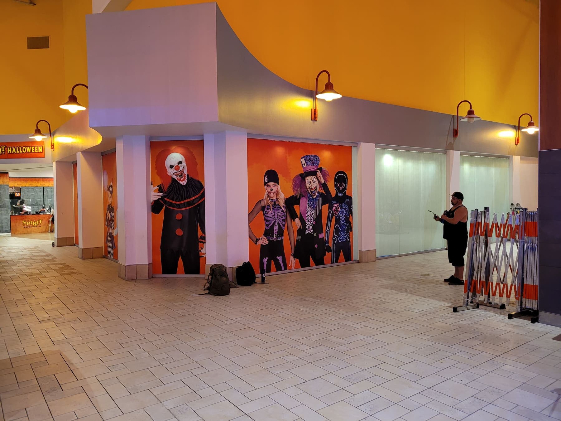 Installer fitting orange costume-character graphics to a mall storefront