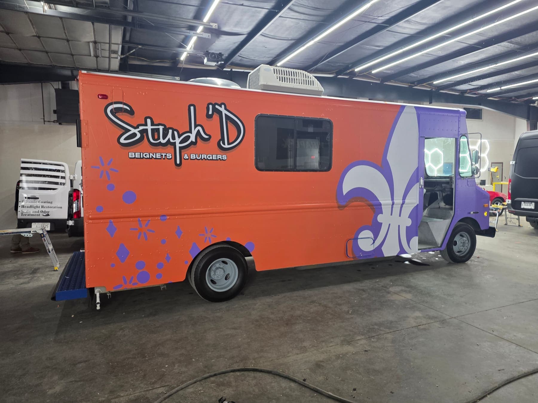 Orange and purple Stuph'D Beignets and Burgers food truck with fleur-de-lis artwork