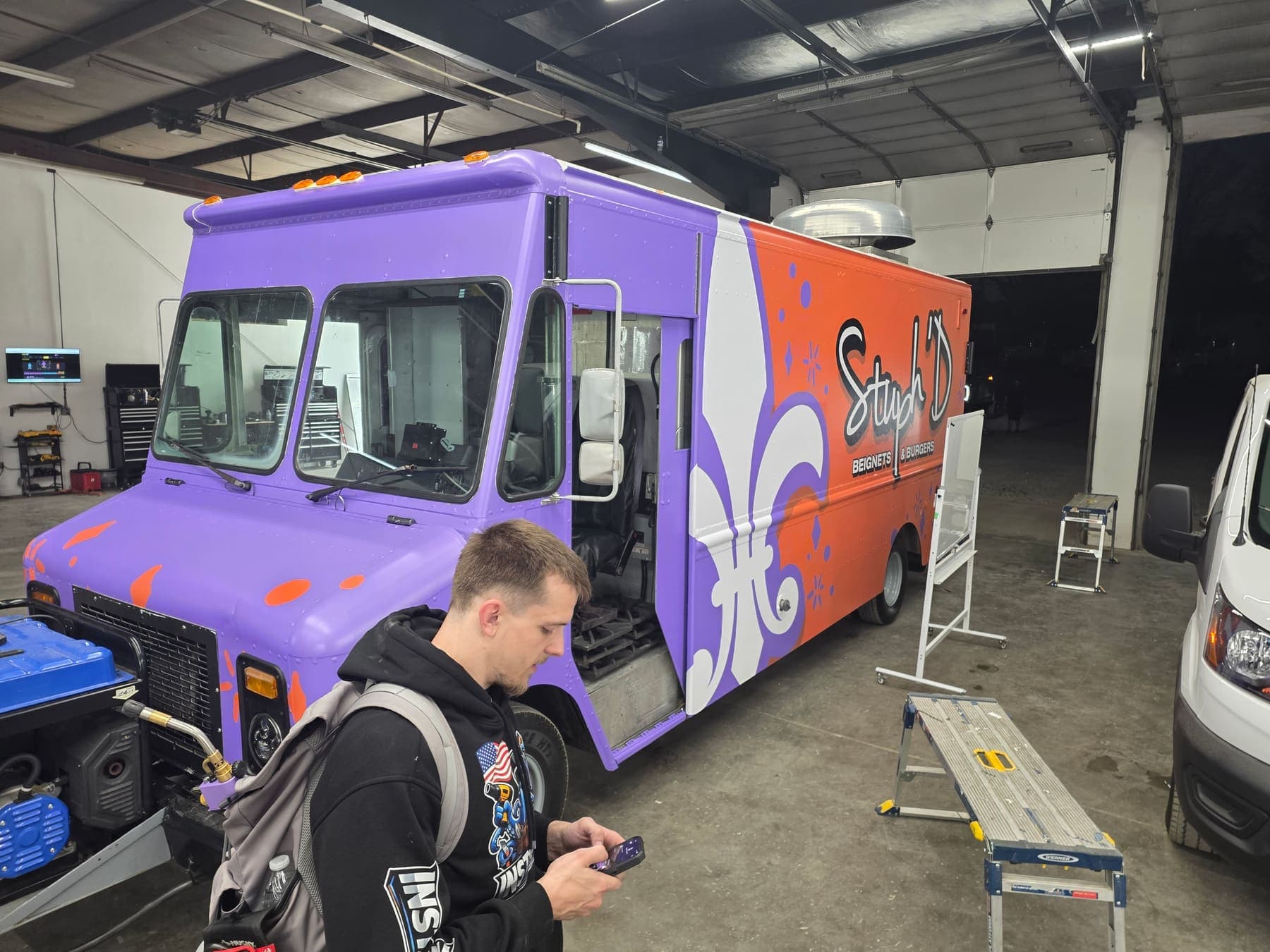 Purple food truck part-way through its wrap install inside the shop