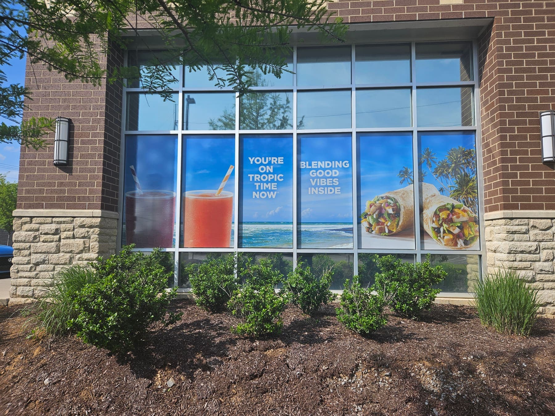 Tropical Smoothie Cafe exterior windows with bright smoothie and menu graphics